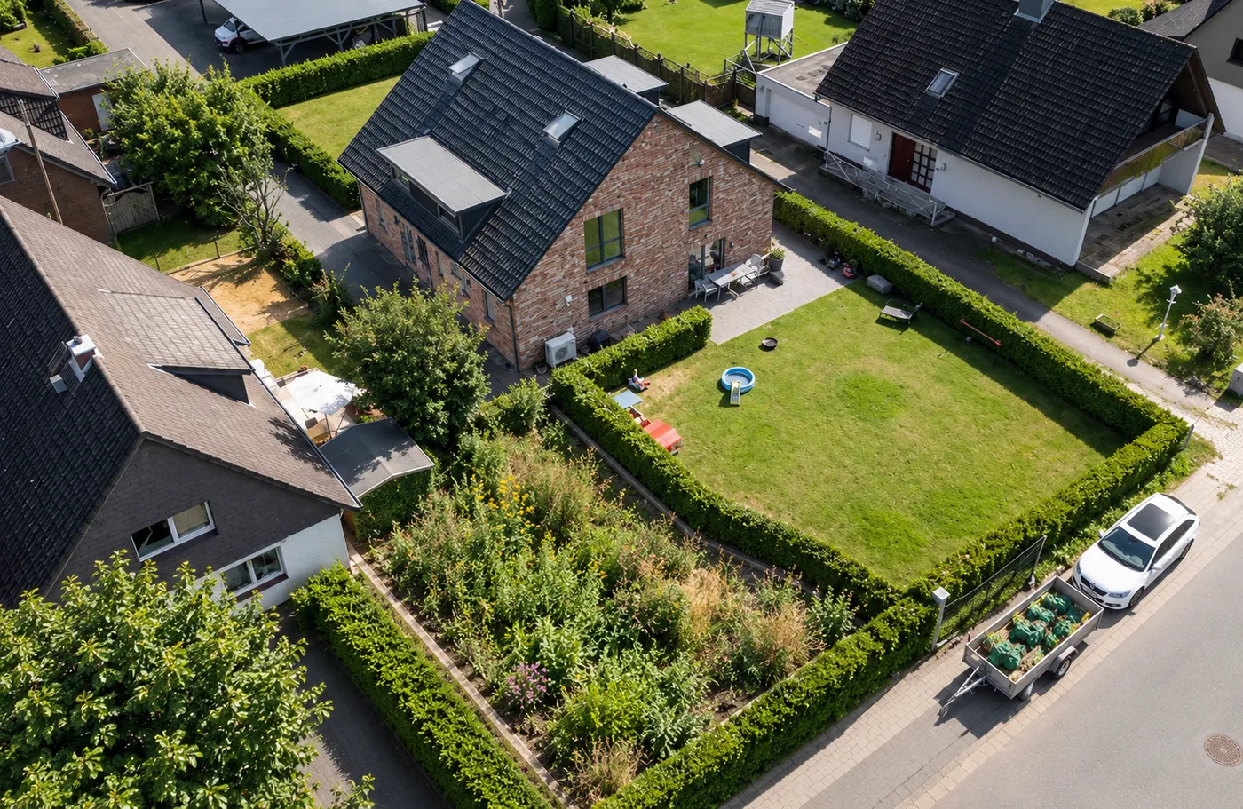 Luftaufnahme eines Gartens mit Rasen, Hecken und Beet
